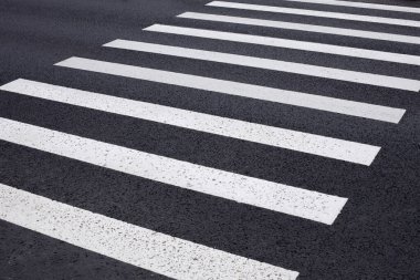 Asfalttan geçen zebra, beyaz çizgiler, yaya geçidi işaretleri, güvenli yol geçişi.