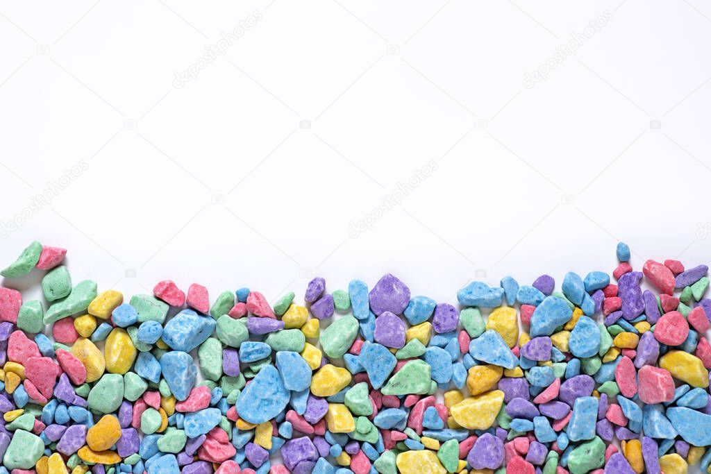 small multi-colored stones, colored soil, sprinkling, decorative stone chips, yellow, pink, blue mosaic pieces on a white background, place for text, mock up for design