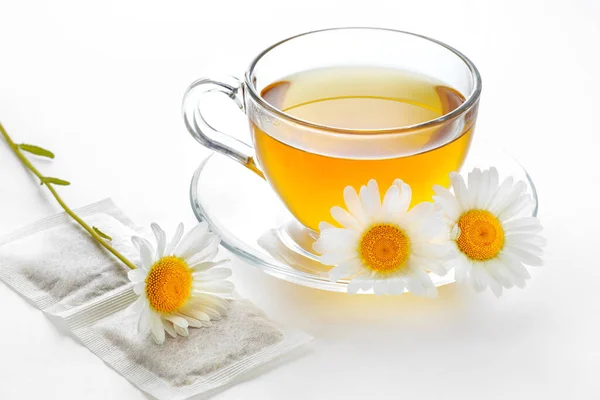 herbal chamomile tea bags, teacup of aromatic green tea with chamomile, on a white background, relaxing natural hot drink, alternative medicine