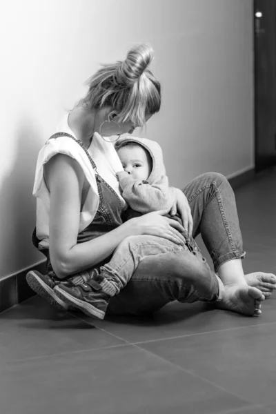 mom breastfeeds the baby, baby sucks breast milk in mom\'s arms, lifestyle, black and white photo