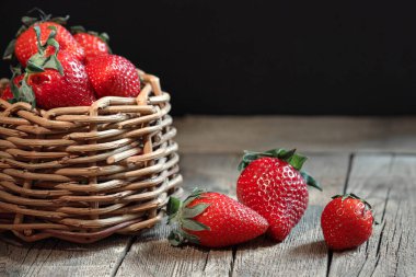 red strawberries in a wicker basket on a wooden table, rustic style, summer breakfast, natural vitamins