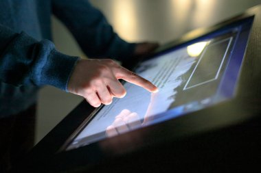 Bir çocuk modern tarih müzesindeki elektronik bir multimedya büfesinin interaktif dokunmatik ekranını kullanıyor. Eğitim, eğitim ve teknoloji kavramı