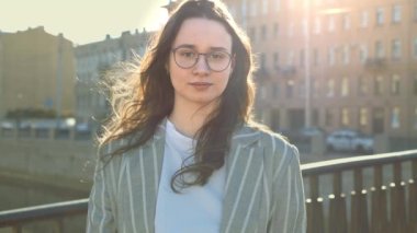 Genç bir kadın kameraya bakar ve gülümser.