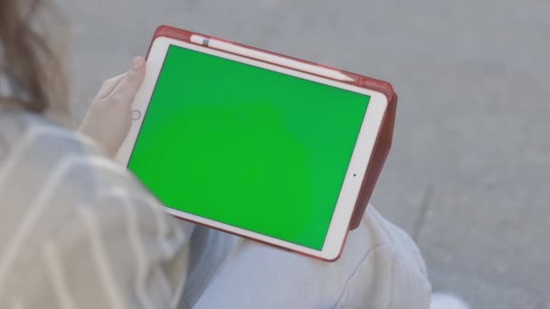 Genç bir kadın dışarıda oturuyor ve tablet üzerinde çalışıyor. — Stok video