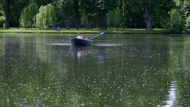 Bootsfahrt im Sommer auf einem Teich im Park, ein junger Mann rudert auf Rudern Hochwertige FullHD-Filmaufnahmen — Stockvideo