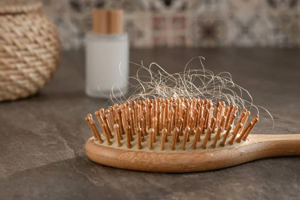 wooden massage comb for hair with hair on it after combing, hair loss concept, alopecia treatment, effects of covid, stress,