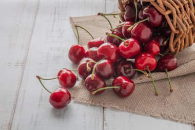 Tahta bir sepetten bir sürü tatlı kiraz meyvesi dökülür. Yaz meyvesi arka planda yakın plan.