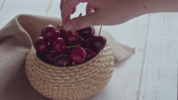 Красивые женские руки берут ягоды вишни из плетеной корзины по кусочкам Высококачественные 4k кадры — стоковое видео