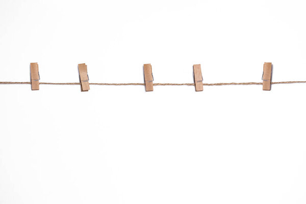 wooden clothespins on a rope on a white background, mock-up for design, copy space, rustic vintage style, clothesline for drying clothes with clothespins