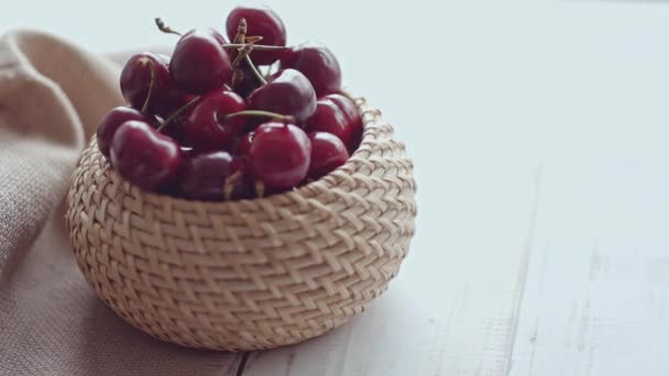 Eine Frau holt Kirschbeeren aus einem Weidenkorb auf dem Tisch — Stockvideo