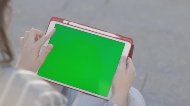 Γυναίκα εργάζεται σε ένα tablet, χτυπώντας με το δάχτυλό της στην οθόνη, πράσινο φόντο, κενό για το σχεδιασμό. Υψηλής ποιότητας υλικό FullHD — Αρχείο Βίντεο