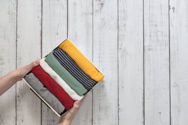 Giysiler düzgünce katlanmış bir kutuda, elleri temiz giysilerle dolu bir kutuda, ahşap bir arka planda, çamaşır servisi...