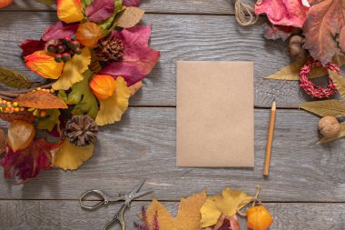 Sonbahar tasarımı, rengarenk dökülen yapraklar ve ahşap masa üzerinde boş el işi kağıtları, sonbahar notu, tasarım için arka plan