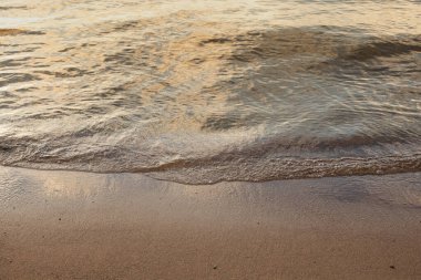 Bir nehrin kumlu kıyısı ya da deniz ya da gün batımında göl, sıcak, yumuşak dalgalar