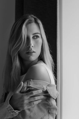 Klasik siyah beyaz bir kadın portresi pencerenin kenarında, gün ışığında, makyajsız, yumuşak gölgeli.,