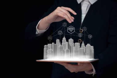 Elinde büyük bir şehrin sanal görüntüsü olan bir tablet ve akıllı şehirde kablosuz internet, telefon, bilgisayar, bulut, küresel internet bağlantısı, 5G iletişim, internet, büyük veri, bulut teknolojisi konsepti bulunan bir tablet var.