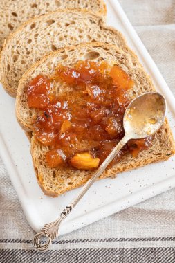 Ev yapımı elma reçeli reçeli karanfil ve cam kavanozdaki organik elmalardan elde edilen tarçınlı marmelat ve antika çay kaşığının yanındaki toptan ekmek. Ev yapımı sonbahar reçeli. Elmalı sandviç tost kahvaltısı 