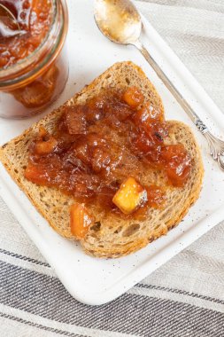 Ev yapımı elma reçeli reçeli karanfil ve cam kavanozdaki organik elmalardan elde edilen tarçınlı marmelat ve antika çay kaşığının yanındaki toptan ekmek. Ev yapımı sonbahar reçeli. Elmalı sandviç tost kahvaltısı 