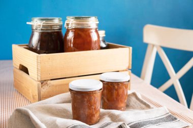 Ahşap kaşığın yanında şeffaf bir bardakta organik elmalardan elde edilen karanfil ve tarçınlı ev yapımı elma reçeli reçeli. Ev yapımı sonbahar reçeli konserveleri.