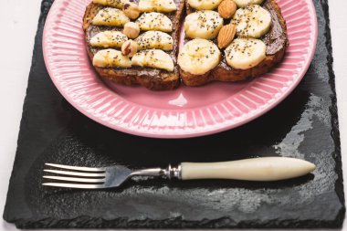 Kızarmış tam buğday ekmeği, çikolatalı fındık ezmeli fındık ezmesi, muz, chia tohumu, badem ve fındıklı tost. Kahvaltı için sağlıklı beslenme