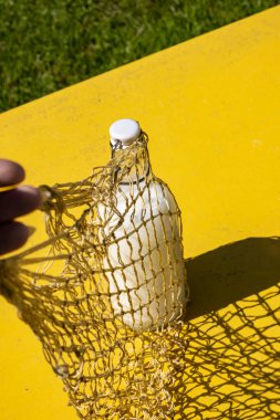 Yeniden kullanılabilir eko ipli bir alışveriş poşetinde, sert gölgeli cam bir süt şişesi. Eski tarz alışveriş için modern yeniden kullanılabilir çanta, çevre dostu plastik ücretsiz konsept, sıfır atık konsept, üst görünüm