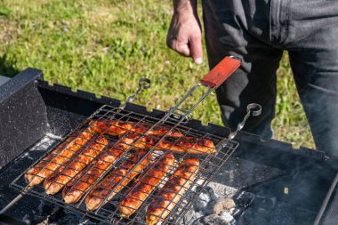 Adam mangalda sosis pişiriyor mangalda, yaz pikniği doğada, barbekü bbq ızgara geleneksel Alman sucuklu sosislisi. 