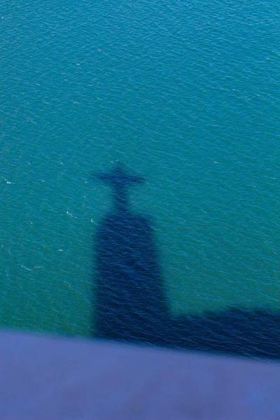 View of shadow on the water of statue catholic monument Sanctuary of Christ the King, Santuario de Cristo Rei, Lisbon, Portugal.  Sacred Heart of Jesus Christ