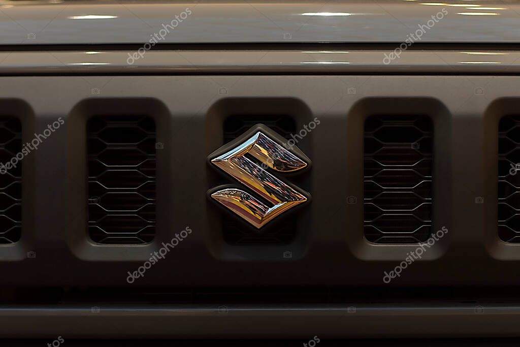 Suzuki logo on the radiator grille. View from the front. Chrome on a khaki-colored grille. Surgut, Russia - December 10, 2020.