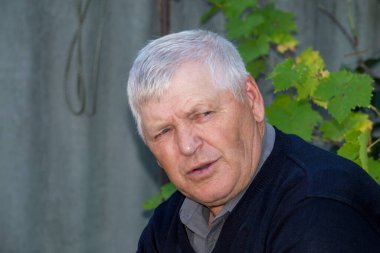 Yaşlı gri saçlı adam kameraya bakmıyor..