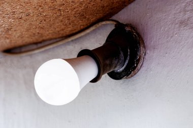 Retro kartuş içinde LED ampul. Beyaz duvara karşı eski evin ön cephesi de dahil. Kavram.