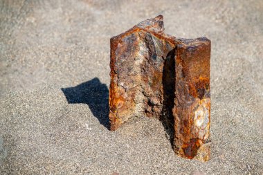 Paslı bir demiryolu kumdan sarkıyor. Güneşli bir yaz günü. Ön görünüm.