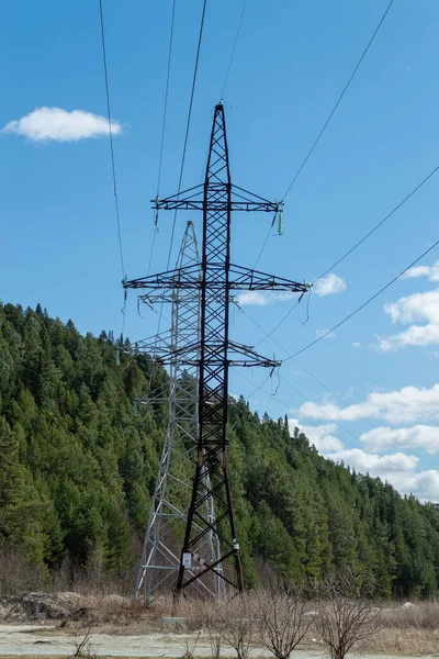 A high-voltage tower in front of the mountain. Sunny good day. Front view.