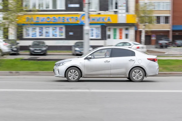 Gray car is driving down street in city. Motion blur. In city of day. Side view. Surgut, Russia - 17, May 2021.