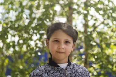  8 yaşındaki kız yeşil ağaca karşı. Gün, yatay çekim Ön görüntü.