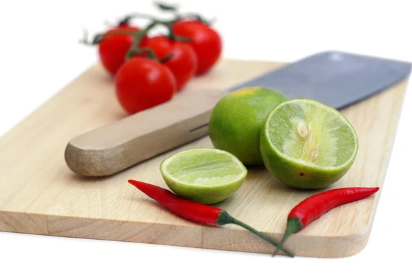 Pimenta, limão e tomate em uma tábua de corte e a faca isola — Fotografia de Stock