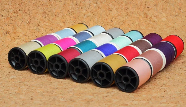 Spools of thread  multicolored on cork board — Stok Foto