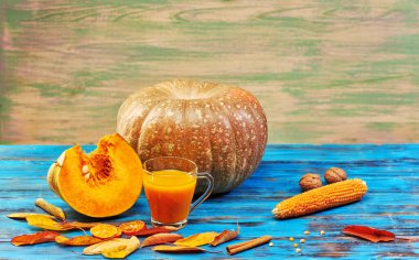 Ahşap mavi arka planda balkabağı suyu ve olgun meyve. Stüdyoda hala hayat var.