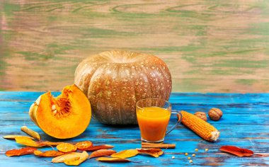 Ahşap mavi arka planda balkabağı suyu ve olgun meyve. Stüdyoda hala hayat var.