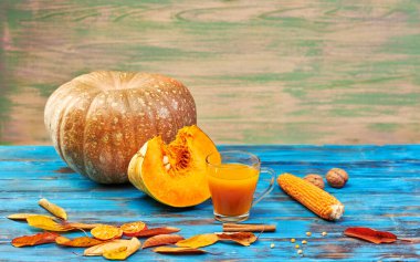 Ahşap mavi arka planda balkabağı suyu ve olgun meyve. Stüdyoda hala hayat var.