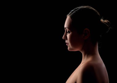 Siyah arka planda poz veren genç bir kız.