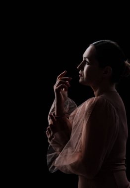 Siyah arka planda poz veren genç bir kız.