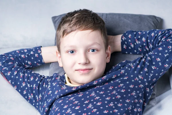 Retrato de un niño mirando a la cámara mientras está acostado en el sofá —  Fotos de Stock