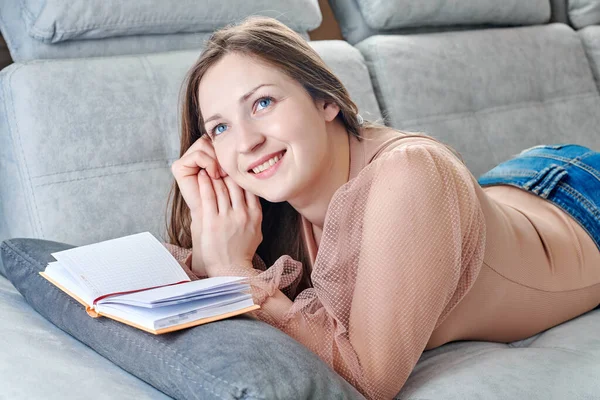 Nettes junges Mädchen liest entspannt auf dem Sofa — Stockfoto