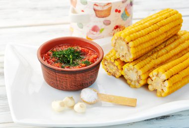 Kaynamış mısır kafalar yan ışıklandırmayla yakın plan bir tabağa konur.