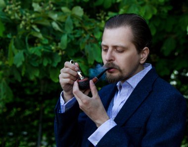 Young beautiful  man smoking tobacco pipe .