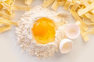 Un ve makarna içinde kırılmış yumurta, erişte yapmak için malzemeler.