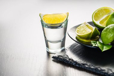 Koyu ahşap arka planda limonlu bardakta alkollü içecek.