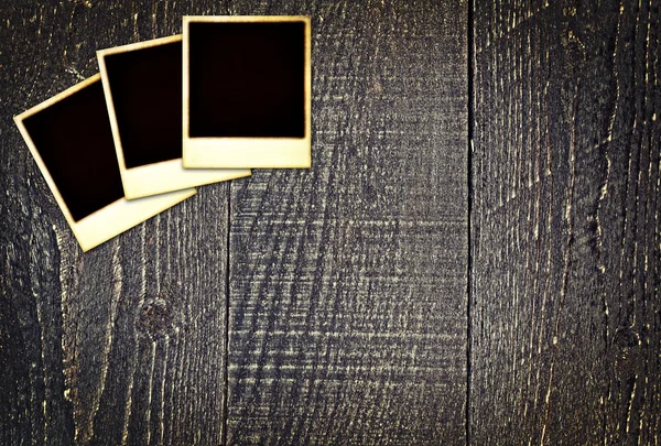 Old weathered blank instant photos on dark wooden table — Stock Photo, Image