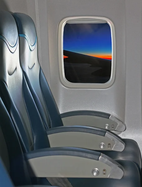 Assentos e janelas dentro de uma aeronave com vista para asa e sóis — Fotografia de Stock