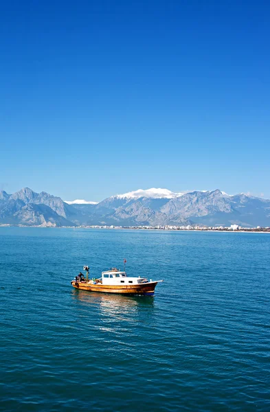 Small fishing boat against snow covered mountains in Antalya Tur — Stock Photo, Image